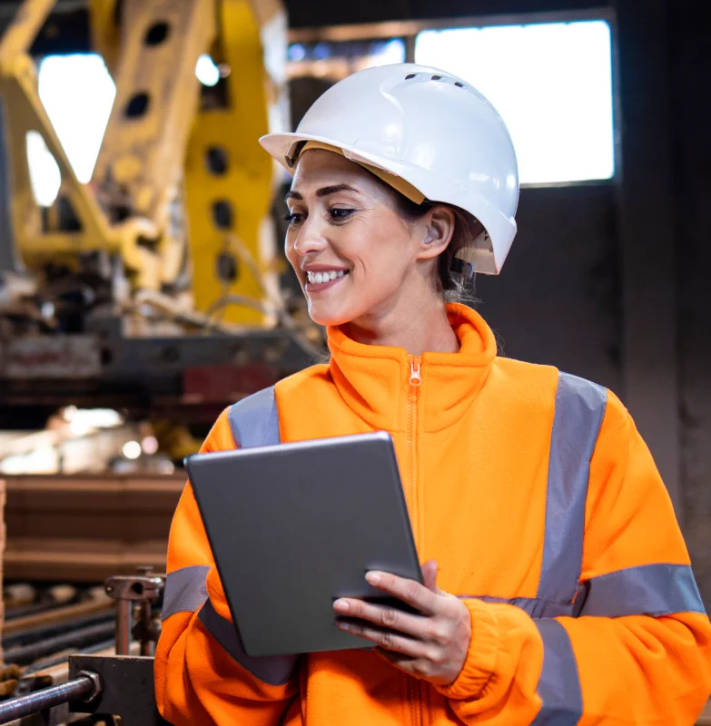 An Asset maintenance officer in an orange jacket is
                  holding a tablet
